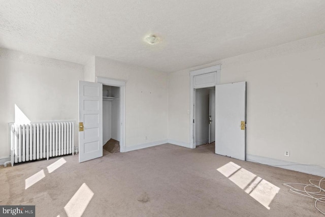 unfurnished bedroom with a textured ceiling, light carpet, baseboards, a closet, and radiator heating unit