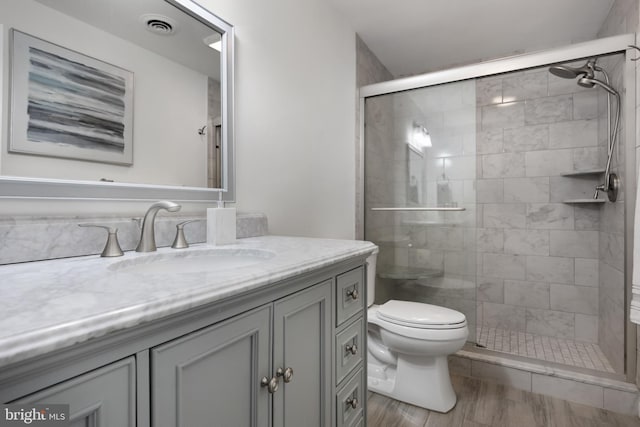 full bath featuring toilet, a shower stall, visible vents, and vanity