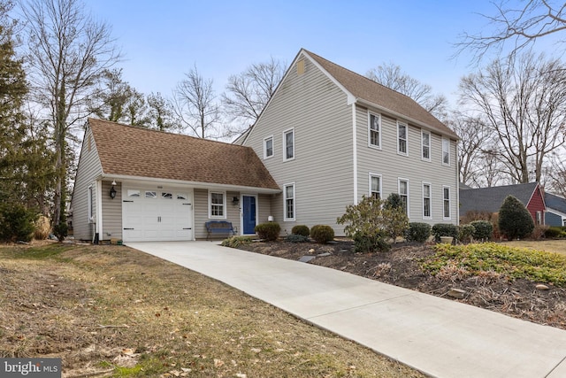 colonial-style house featuring a garage, driveway, and roof with shingles