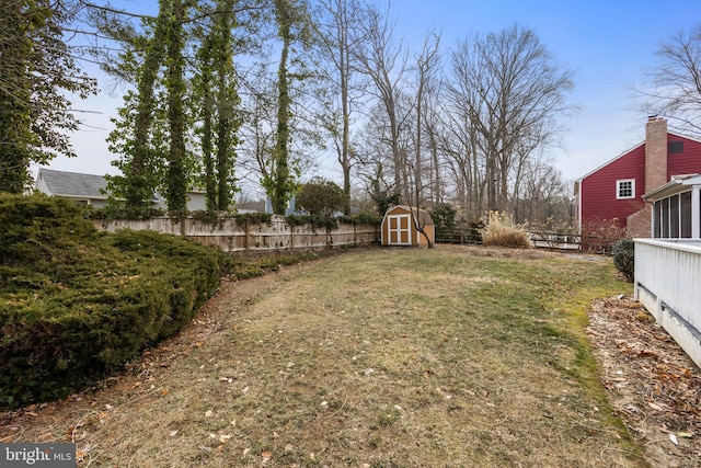 view of yard featuring a storage shed, fence, and an outbuilding