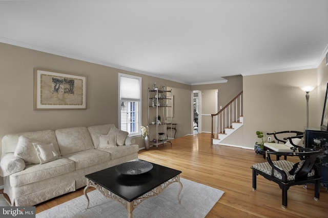 living area featuring crown molding, stairs, baseboards, and wood finished floors