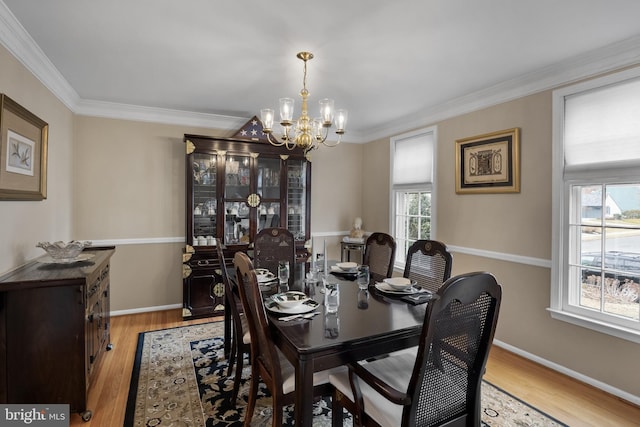 dining area with baseboards, ornamental molding, light wood-type flooring, and a notable chandelier