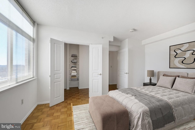 bedroom with multiple windows, a textured ceiling, and baseboards