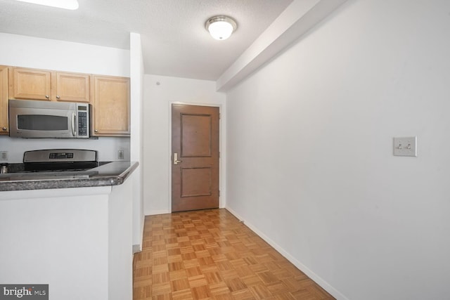 kitchen with dark countertops, baseboards, stainless steel appliances, and a textured ceiling