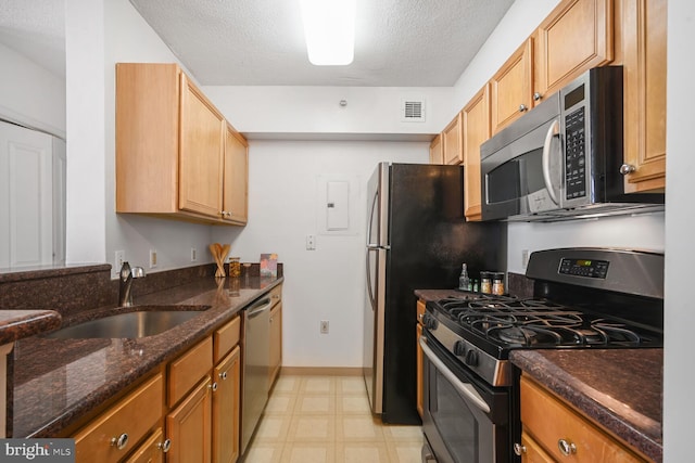 kitchen with light floors, visible vents, appliances with stainless steel finishes, a sink, and dark stone countertops