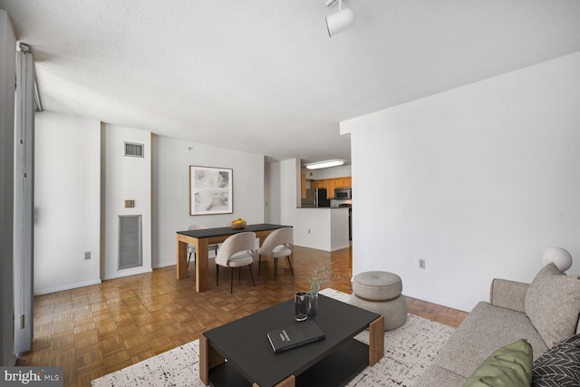 living area featuring a textured ceiling, visible vents, and baseboards