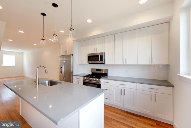 kitchen with appliances with stainless steel finishes, sink, white cabinetry, and a center island with sink