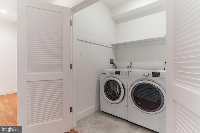 laundry room with washing machine and dryer and light hardwood / wood-style flooring