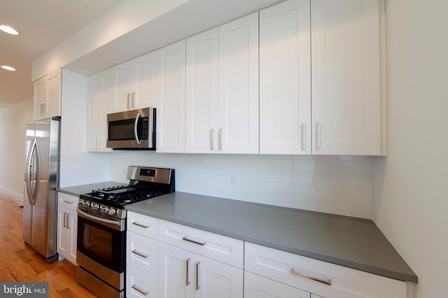 kitchen featuring white cabinets, appliances with stainless steel finishes, light hardwood / wood-style flooring, and tasteful backsplash