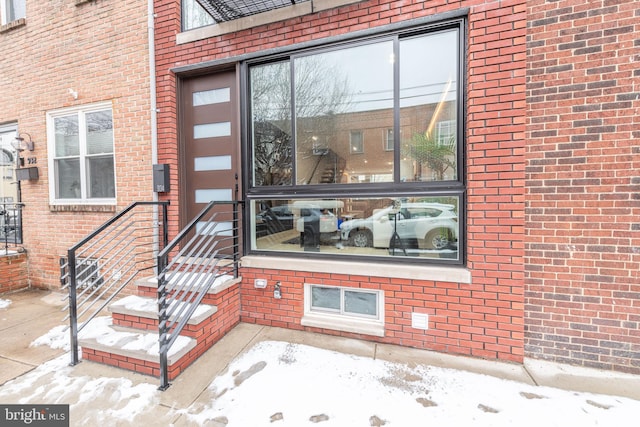 snow covered property entrance with brick siding