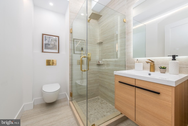 full bathroom with toilet, a stall shower, vanity, wood finished floors, and baseboards