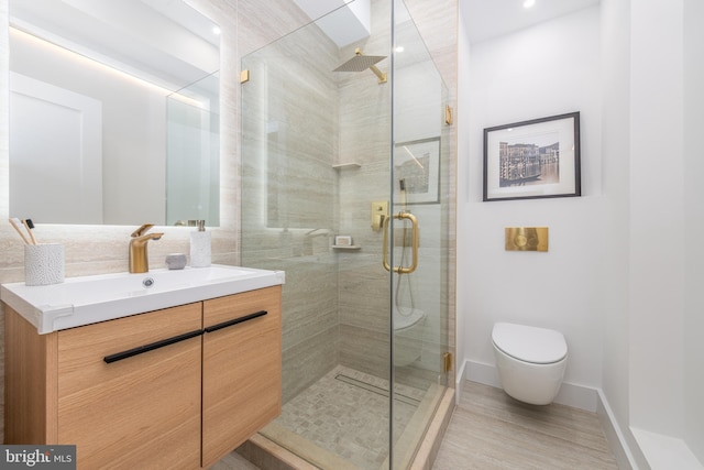 bathroom featuring toilet, wood finished floors, vanity, baseboards, and a stall shower