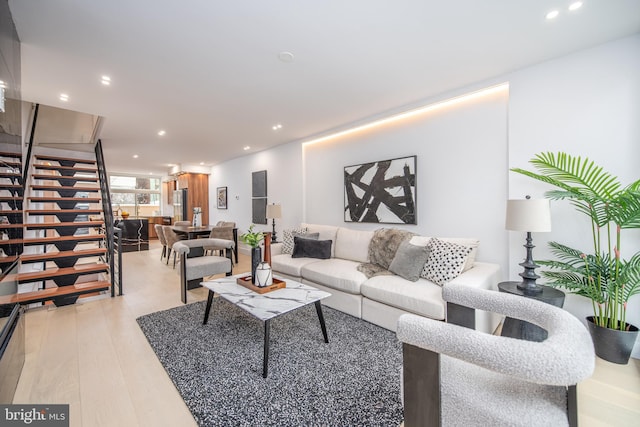 living room featuring light wood-style flooring, stairway, and recessed lighting