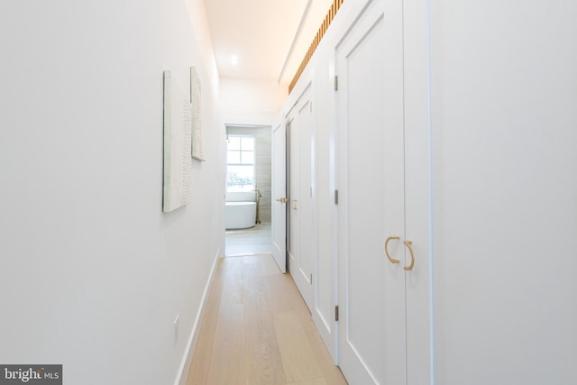 corridor featuring light wood finished floors and baseboards