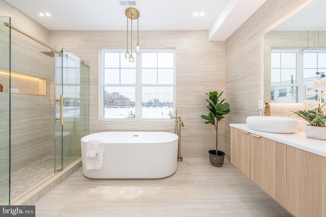 full bathroom featuring tile walls, visible vents, a shower stall, vanity, and a freestanding tub