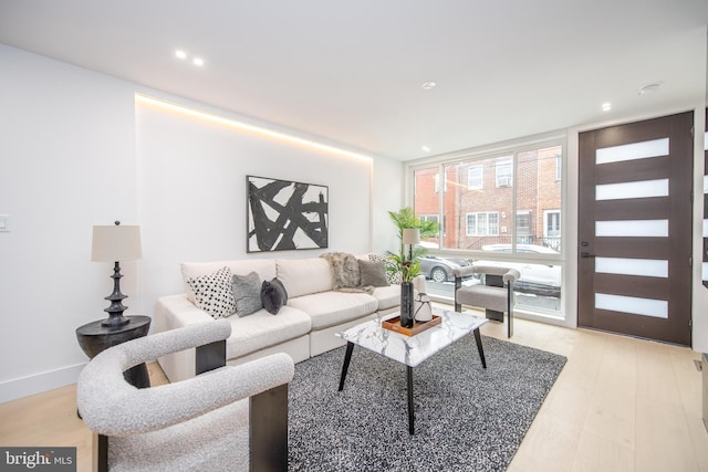 living room featuring light wood-style floors, a wall of windows, and recessed lighting