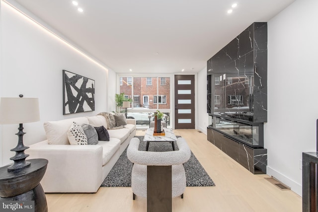 living room featuring baseboards, recessed lighting, wood finished floors, and floor to ceiling windows