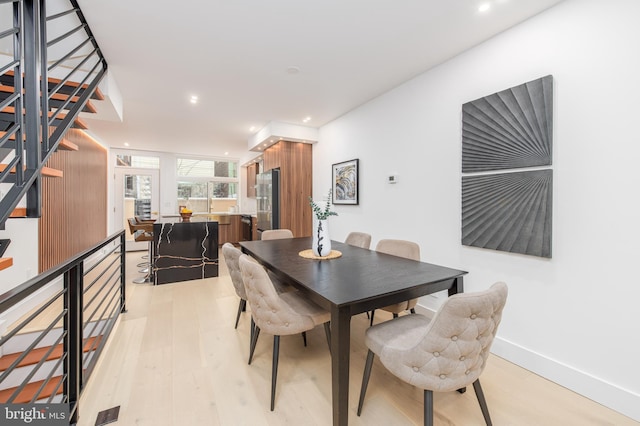 dining area featuring light wood finished floors, baseboards, and recessed lighting