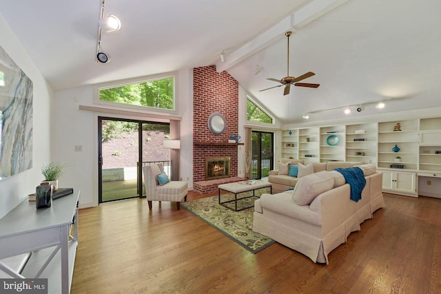 living room with light wood-type flooring, beamed ceiling, a fireplace, track lighting, and high vaulted ceiling