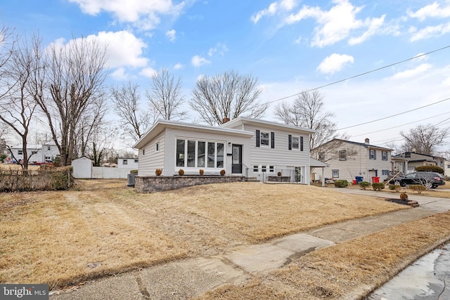 view of front of house with a front yard, concrete driveway, and fence