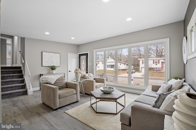 living area with recessed lighting, a healthy amount of sunlight, stairway, and wood finished floors