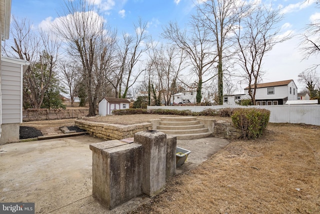 view of yard featuring an outbuilding, fence, a patio, and a shed