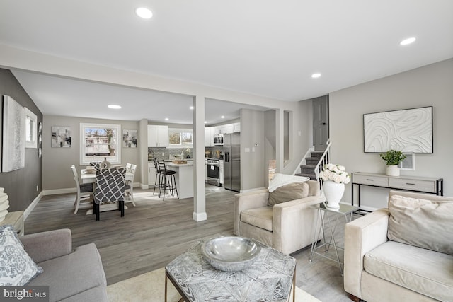 living area featuring stairs, baseboards, wood finished floors, and recessed lighting