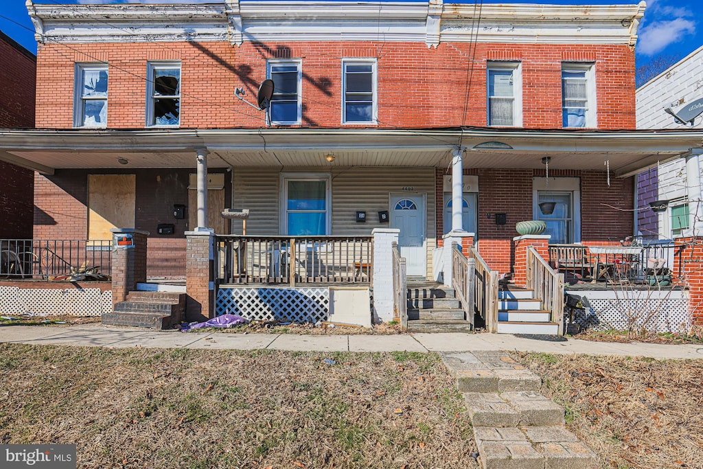 townhome / multi-family property with a porch and brick siding