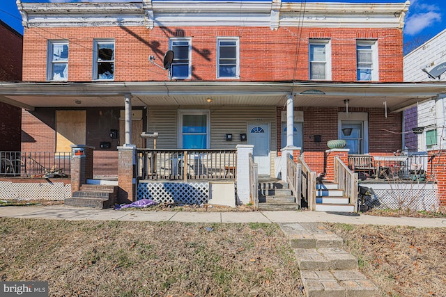 townhome / multi-family property with a porch and brick siding