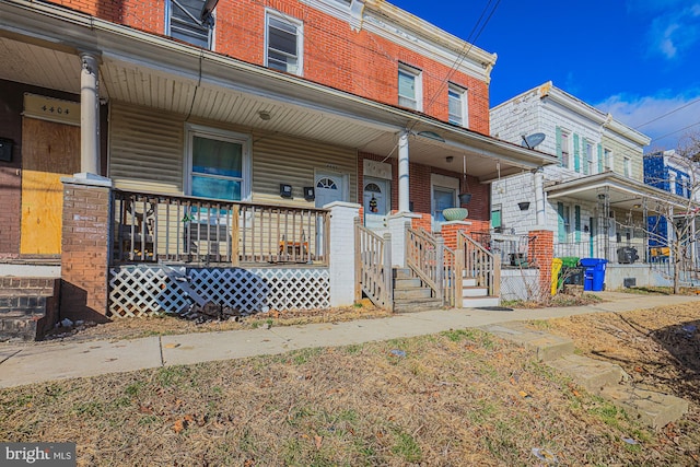 townhome / multi-family property featuring a porch and brick siding