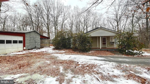 view of front of property featuring a garage, covered porch, cooling unit, and an outbuilding