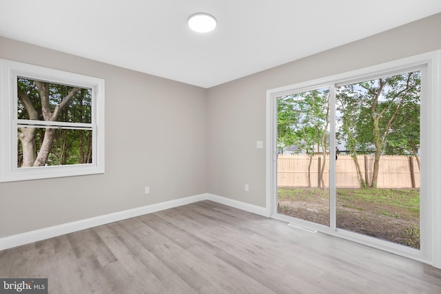 unfurnished room with baseboards, healthy amount of natural light, and wood finished floors