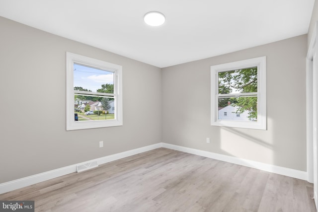 spare room featuring plenty of natural light, light wood-style floors, and baseboards