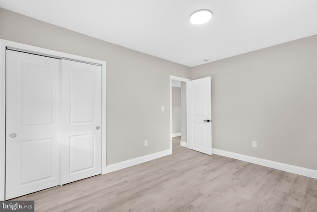 unfurnished bedroom with light wood finished floors, baseboards, and a closet