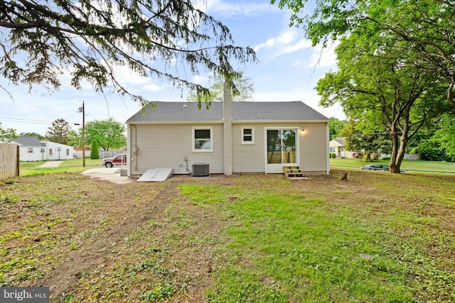 back of property featuring entry steps, a yard, and central AC
