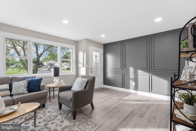 living room with a decorative wall, recessed lighting, and light wood-style flooring