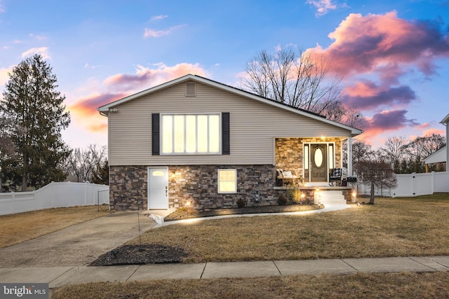 tri-level home with fence, concrete driveway, and a front yard