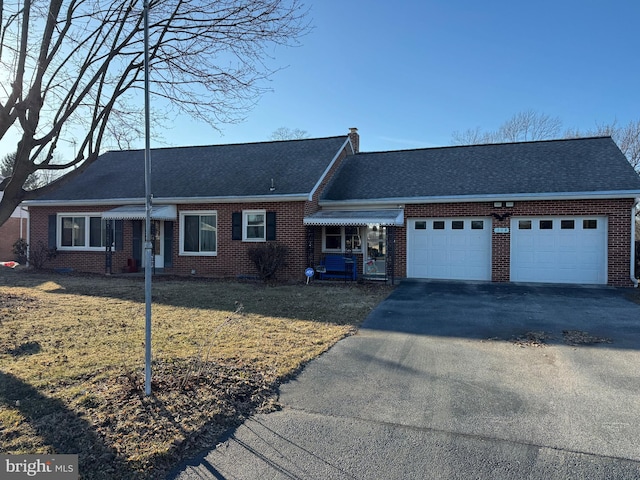 view of front of home featuring aphalt driveway, a front yard, and brick siding