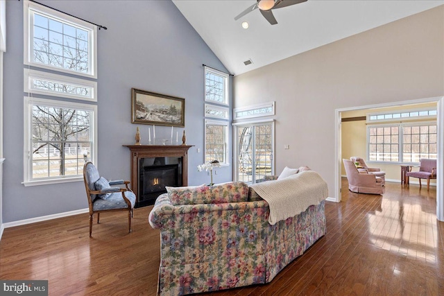 living room with ceiling fan, wood finished floors, a healthy amount of sunlight, and a glass covered fireplace