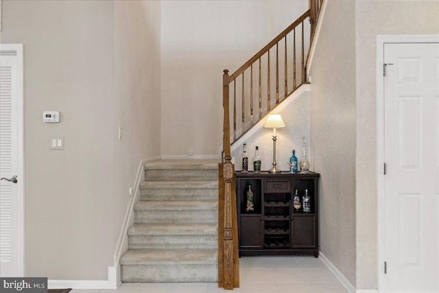 stairway with tile patterned floors and baseboards