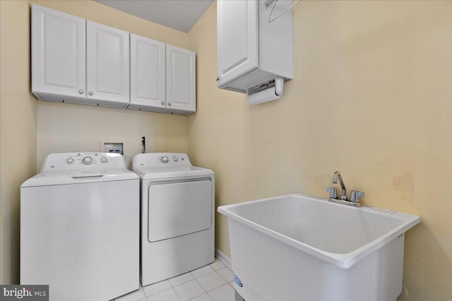 washroom featuring washing machine and dryer, light tile patterned floors, cabinet space, and a sink