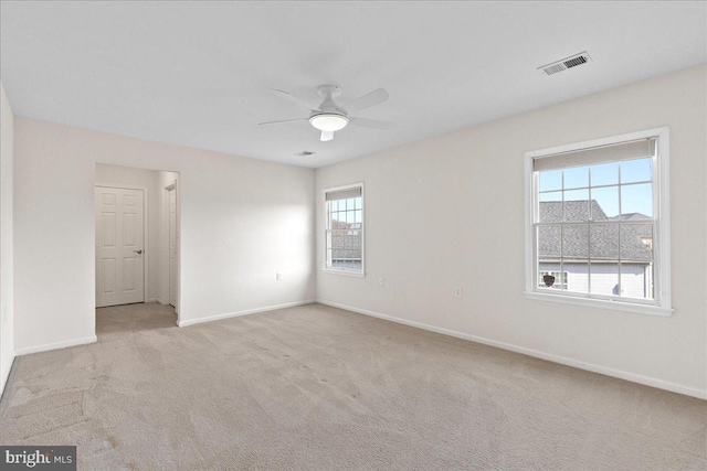 carpeted spare room featuring visible vents, baseboards, and a ceiling fan