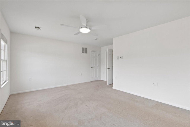 unfurnished room featuring visible vents, baseboards, light colored carpet, and ceiling fan