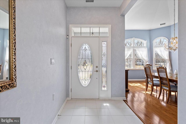 foyer featuring an inviting chandelier, wood finished floors, visible vents, and baseboards