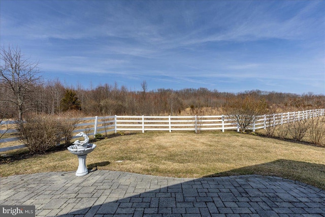 view of yard with a patio, fence, and a wooded view