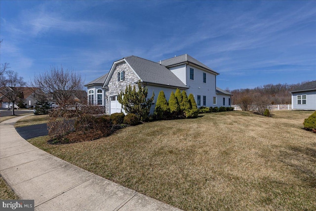 view of side of property with a lawn, a garage, and fence