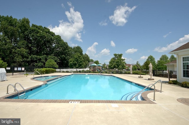 pool with fence, a hot tub, and a patio area