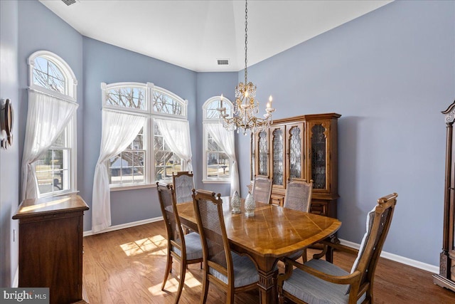 dining area featuring an inviting chandelier, wood finished floors, visible vents, and baseboards