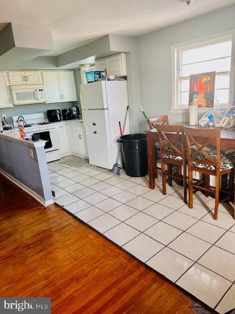 kitchen with white appliances, light tile patterned floors, and white cabinets