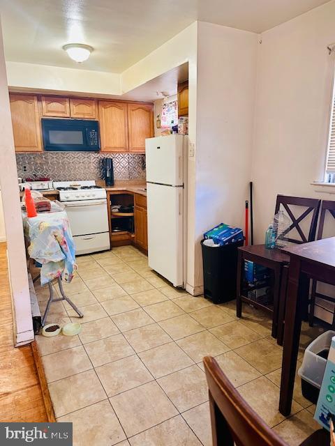 kitchen with light tile patterned floors, white appliances, and tasteful backsplash